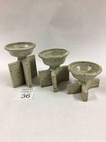 Set of 3 oatmeal cream glazed stoneware candlesticks of varying sizes.