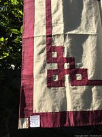 Close-up photo showing maroon geometric corner pattern on beige cotton fabric with maroon border of the Tibetan Buddhist door curtain.