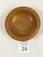 Top-down image showing detailed symmetrical floral and geometric chip carving in bowl base and geometric carved border on rim.