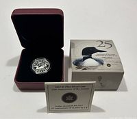 Set showing the silver coin in a black velvet inset within a maroon presentation box, alongside the original outer box and certificate card.