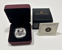 Photo showing the coin in a protective case inside a dark red, velvet-lined display box with certificate and original Royal Canadian Mint box present.