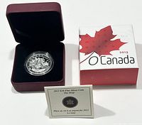 Photo showing the 2013 $10 fine silver coin in protective casing inside a velvet-lined maroon display box, certificate of authenticity and outer branded box with Canadian maple leaf design.