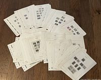 Over 80 off-white stamp pages spread out on a wooden floor, each page with multiple Canadian stamps affixed.