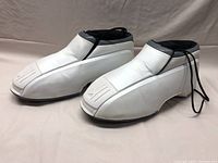 Front three-quarter profile of both sneakers showing white uppers and grey collars