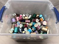 Top-down view of the bin showing various thread spools with different colors and brands.