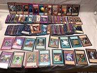Large assortment of Yu-Gi-Oh cards laid out on a flat surface, showing multiple monster, spell, and trap cards in rows.