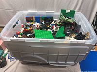 Front view of bin with assorted LEGO pieces and green base plates inside