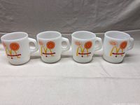 Four white vintage McDonald's coffee mugs lined up, displaying the front logos and designs.