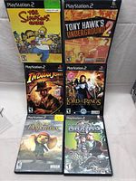 Photo of all six game cases showing cover art including The Simpsons Game, Tony Hawk's Underground 2, Indiana Jones and the Staff of Kings, Lord of the Rings: The Return of the King, The Tale of Despereaux, Maximo.