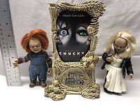 Full setup showing Chucky and Bride of Chucky figures with themed Movie Maniacs display frame and ruler for scale
