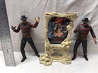Front view showing two Freddy Krueger figures on either side of the Movie Maniacs standee with horror theme details