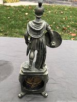 Rear view showing soldier figure standing on rectangular base with paw feet, clock mechanism compartment visible.