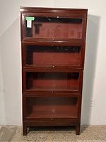 Front view of Globe-Wernicke barrister bookcase assembled with four stacking sections, base and top, faux mahogany finish, glass-front doors.