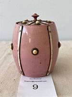 Front side view of the pink barrel-shaped tea caddy jar showing its vertical metal ribs and knob accents.