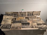 Overview of over twenty 14×11 black and white theatre group photographs laid out on a table.