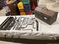 Vintage mechanic tools laid out on table including ratchets, wrenches, sockets, and toolbox