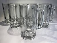 Eight German style large vintage glass beer mugs shown standing upright in a close group, clear solid glass with starburst base pattern