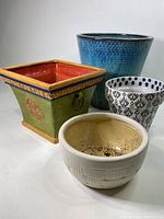 Four ceramic planters arranged together showing various colors and shapes.