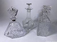 Front angle of three decanters including Dublin Crystal labeled decanter with geometric cuts and two clear glass decanters.