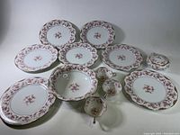 Full view of the 12 piece Noritake china lot arranged on a surface, showing plates, teacups, creamer, sugar bowl, and serving bowl.