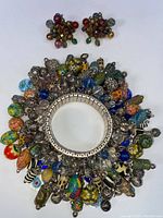 Photo of the vintage stretch cha cha bracelet featuring a wide silver-toned band with numerous dangling multicolored beads and metal charms in various shapes and sizes.