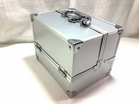 Closed view of silver aluminum makeup train case showing the metal corner reinforcements, handle, and latch lock on top.