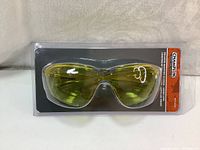 Front view of Champion ballistic shooting glasses in sealed packaging, showing amber lenses and backing card with branding and details.