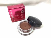 Photo shows the closed jar of Shiseido Shimmering Cream Eye Color with the product box. The jar is round clear glass with black lid featuring Shiseido branding, and the box is a deep red color with product details visible.