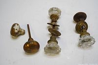 Four vintage door knobs including two clear faceted glass knobs and two metal knobs with stems, displayed on a white surface.