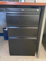Front view of the black metal Staples file cabinet showing the three drawers and lock on the top drawer.