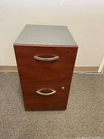 Front view of the 2 drawer office file cabinet showing the wood-finish drawer fronts, metal handles, and lock on lower drawer.