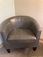 Single gray barrel chair with square wooden legs shown against a blank wall