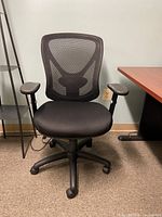 Front view of black office chair with mesh back, padded seat, black adjustable armrests, and five-legged base with casters.