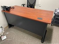Photo of the Bush Business Furniture office desk showing the woodgrain finish desktop, gray modesty panel, black legs, and cable grommet.
