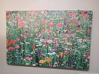 Canvas wall art showing a colorful wildflower field with detailed flowers in multiple colors including red, pink, white, yellow, and purple.