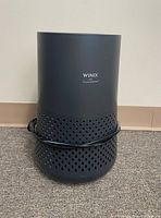 Photo showing black Winix Plasmawave A230 cylindrical air purifier with a perforated bottom section and cord wrapped around unit.