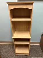 Front view of the light oak wooden shelving unit showing adjustable shelves and open back panel design.