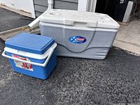 Photo of two Coleman coolers, one large gray with can holders and one small blue beverage cooler.