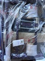 Leg Magic DLX exerciser sealed in clear plastic packaging, showing purple metal frame and white padded footrests with springs.