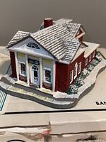 Close-up of the miniature bank building sculpture showing detailed roof, brickwork, and front facade.