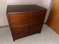 Front view of solid wood 2-drawer file cabinet, showing wood grain and drawer alignment without handles, with keyhole on top drawer.