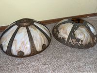 Two stained glass lamp shades with cream and brown marbled glass panels and ornate metal overlay, displayed side by side