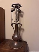Full view of vintage bronze-tone metal lamp with bird motif and dual lamp sockets on top.