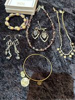 Photo of the mixed vintage jewelry lot showing bracelets, necklaces, and earrings with a SOL Signs of Life charm bracelet.