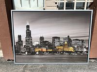 Front view of large framed city skyline picture with selective color highlights.