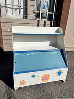 Front view of vintage kids toy box with chalkboard door and colorful flower designs