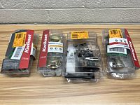 Four Kwikset door knob and lock sets in original packaging shown side by side on table.