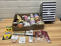 Box with multiple rolls of ribbon in various colors and patterns, Crayola colored pencils, beads, trims, and a decorative box with 'PRETTY THINGS INSIDE' text