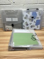 Plastic organizers placed in background with scrapbooking binder and clear zipper bag in front on wood table