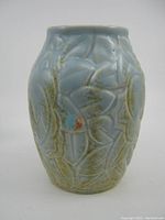 Front view of 1930's light blue glazed embossed floral Beswick Ware vase showing Art Deco style and some glaze wear.